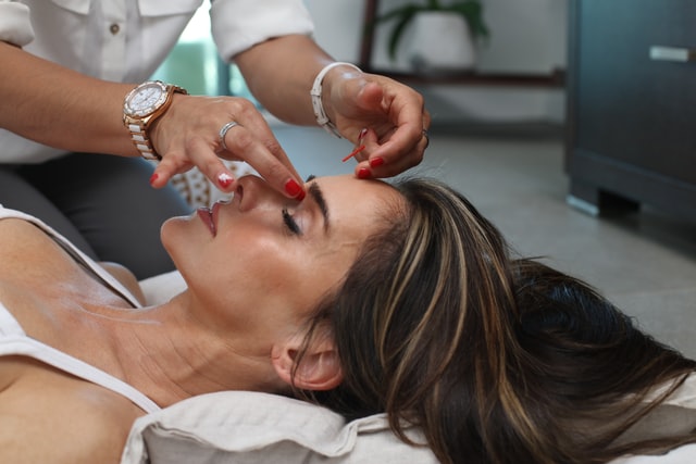 A professional skincare expert administers botox injections to another woman’s forehead